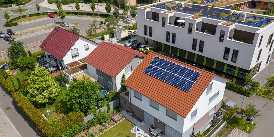 Photovoltaik-Anlagen auf Dächern von Wohnhäusern, bepflanzte Gärten und am Straßenrand parkende Autos, Sicht von oben aus Vogelperspektive